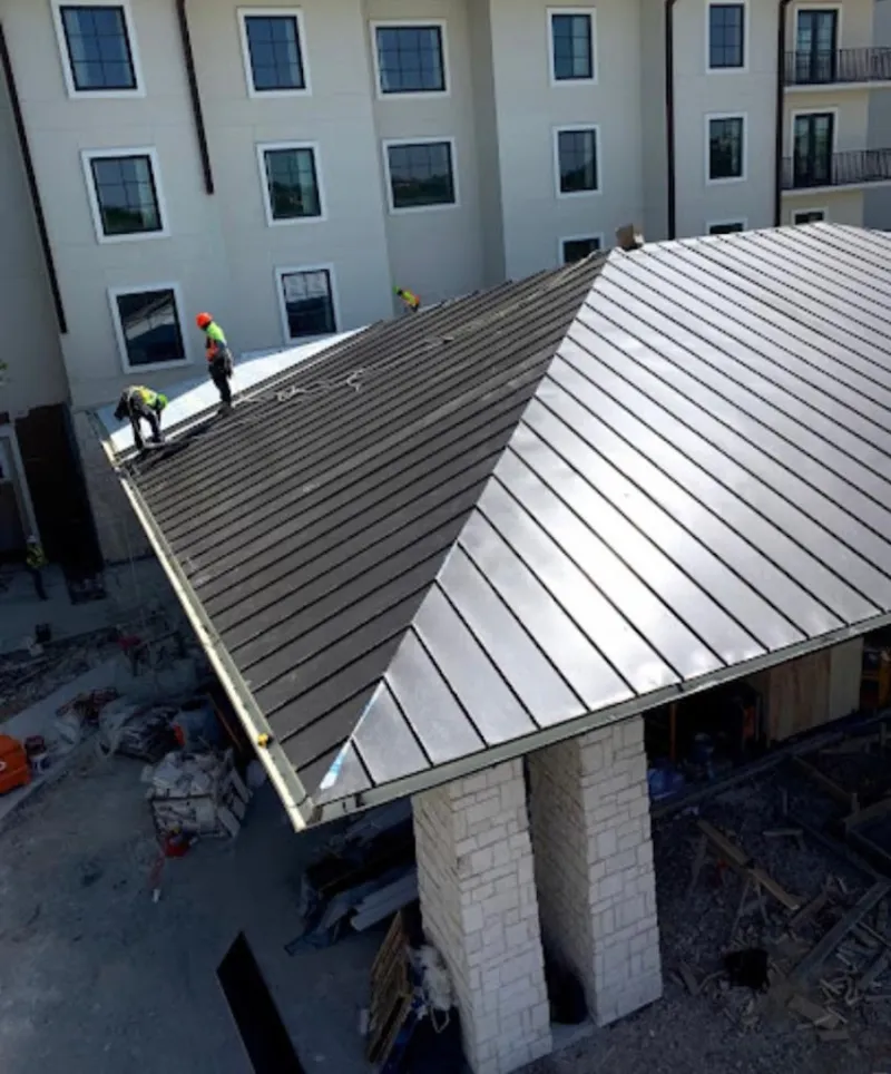 Crew installing standing seam metal roof panels on a commercial project in Whitewater